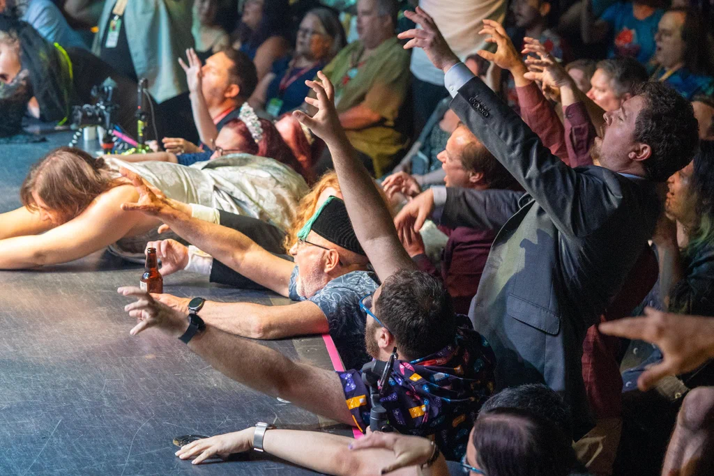 People on stage reaching out to a performer during the JoCo Zombies event at JoCo Cruise 2025.