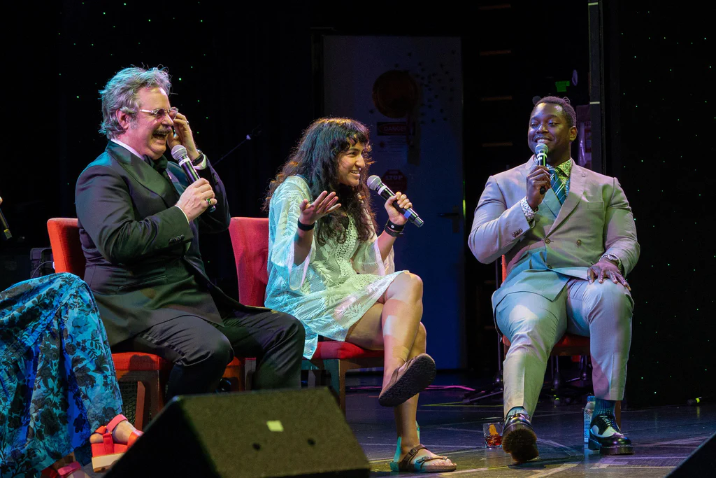 A group of three people on stage at JoCo Cruise 2025, engaging in a lively talk or performance.