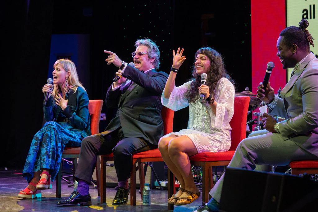 Four people sitting on stage at JoCo Cruise 2025, engaging with the audience during a panel or performance.