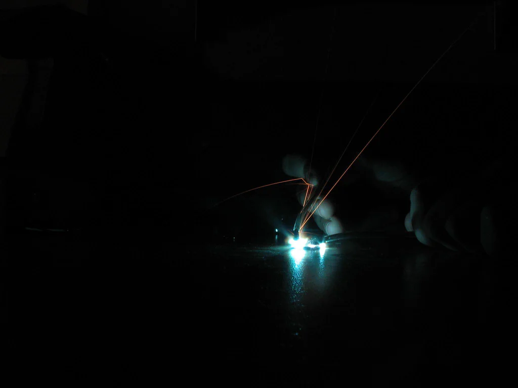 A high-voltage device sparking, with bright electrical discharges and sparks visible in the dark.