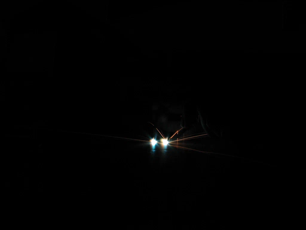 A high-voltage device is sparking, with bright blue and orange electrical discharges visible against a dark background.