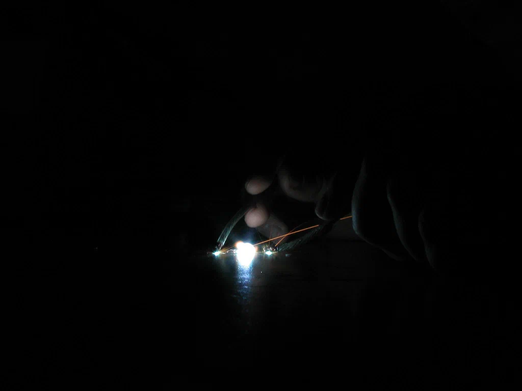 A high-voltage device sparking, with visible bright sparks and electrical arcs in a dark environment.