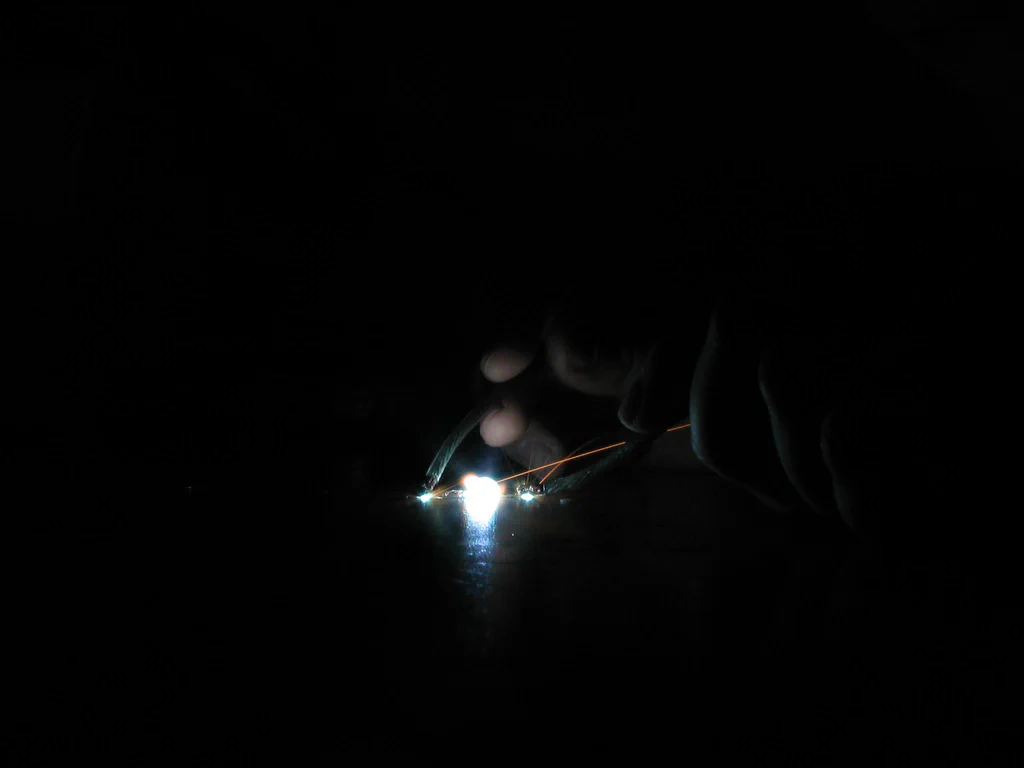 A high-voltage device sparking, with visible bright sparks and electrical arcs in a dark environment.