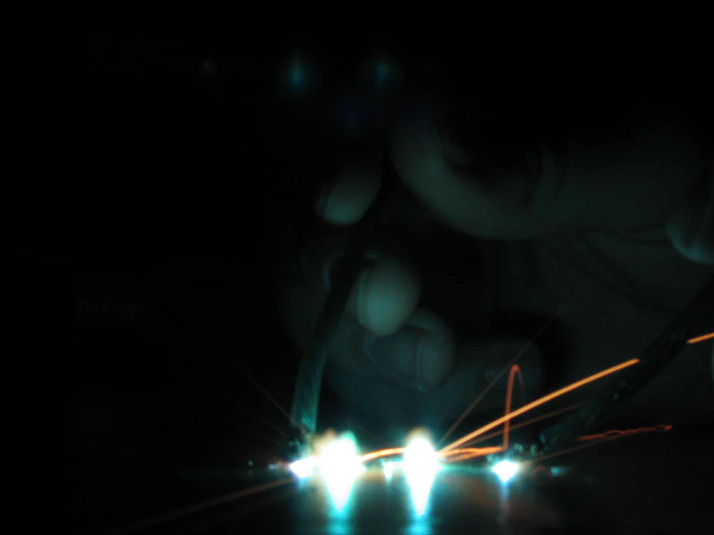 A person is welding or working with a high-voltage device, producing bright sparks and electric arcs in a dark environment.