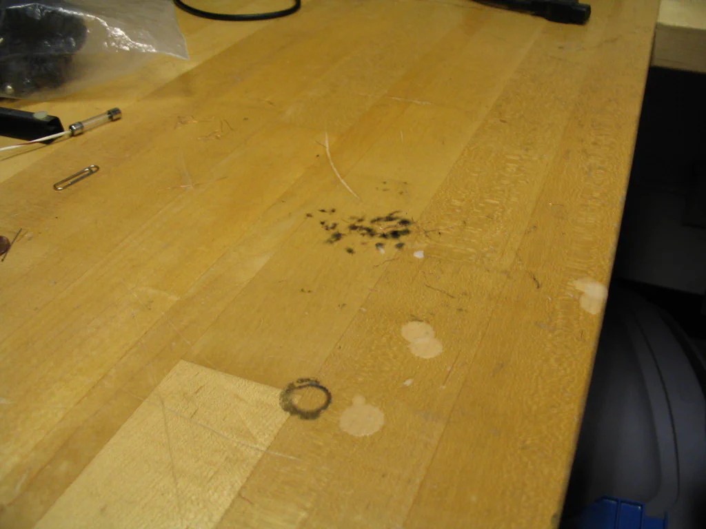 A high-voltage device is sparking, with visible electrical discharge, on a workbench surface.