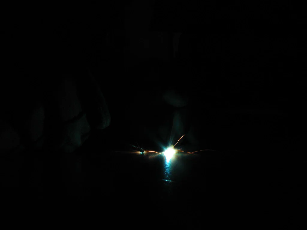 A high-voltage device sparking with bright electrical discharge in a dark environment.