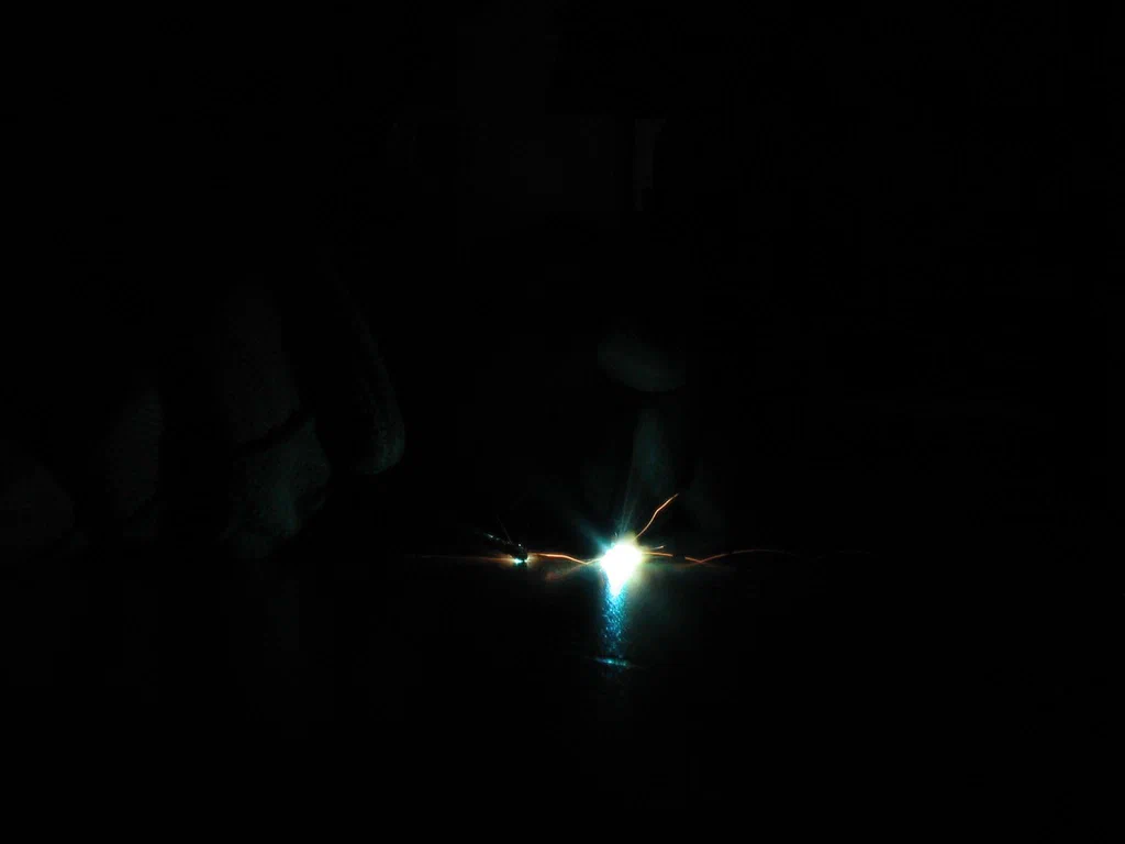 A high-voltage device sparking with bright electrical discharge in a dark environment.