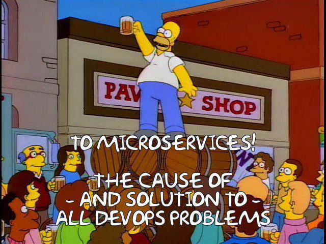 Homer Simpson standing on a bar counter, holding a beer mug, with people gathered around him in a pub or tavern setting.