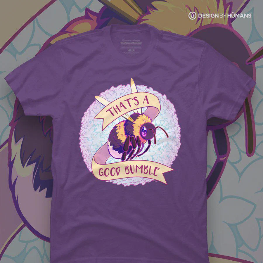 A purple T-shirt featuring a cartoon illustration of a bee with large, shiny eyes, surrounded by a fluffy background, and a banner that reads "THAT'S A GOOD BUMBLE."