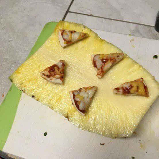 A pineapple slice with small pizza slices placed on top, resembling toppings.