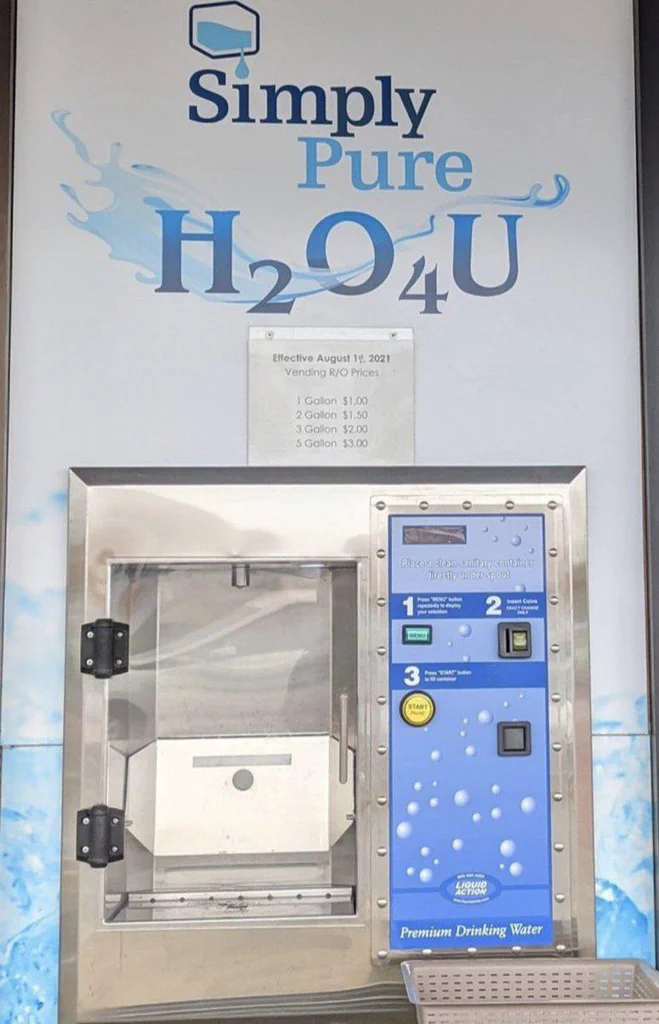 A vending machine for purified drinking water with a sign indicating prices based on gallon quantity.